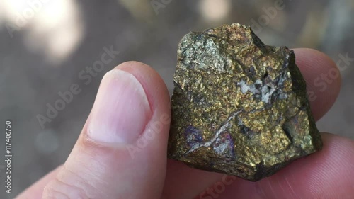 Close up shot of the hand of an anonymous prospector or geologist holding a rock chip sample of copper sulfide ore used in the mining industry to extract copper base metal to sell as a commodity.