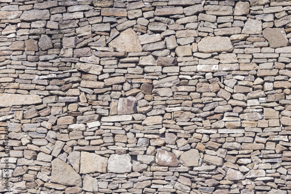 Old grey and brown rough stone wall, closeup texture background, selective focus, shallow DOF