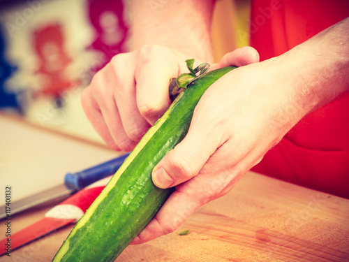 Man preparing vegetables salad peeling cucumber