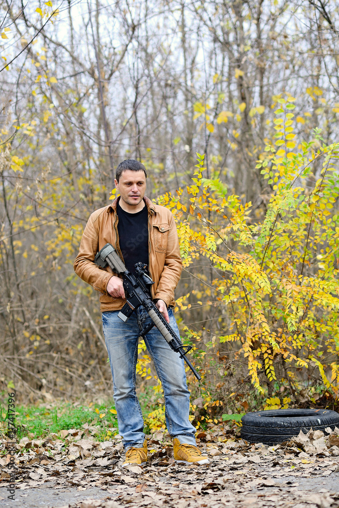 pensive man with an automatic weapon in the woods