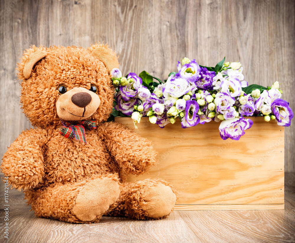 Obraz premium Flowers and a teddy bear on wooden background