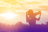 Silhouette women play violin sunset background