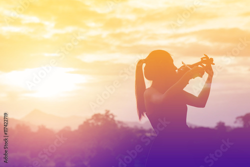 Silhouette women play violin sunset background