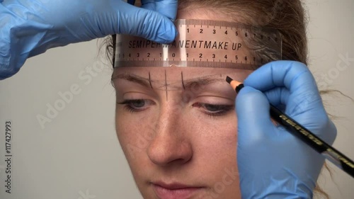 Microblading procedure. Master marks out customer's eyebrows