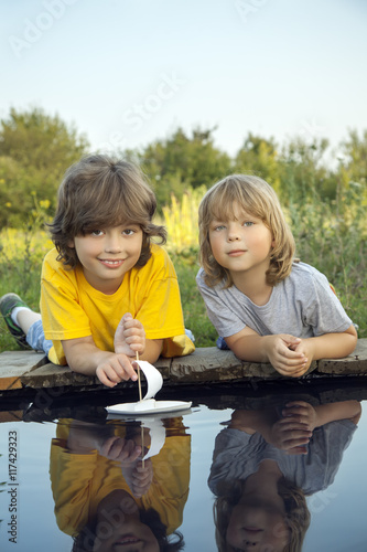 Two boys allowed paper boats from the pier of river