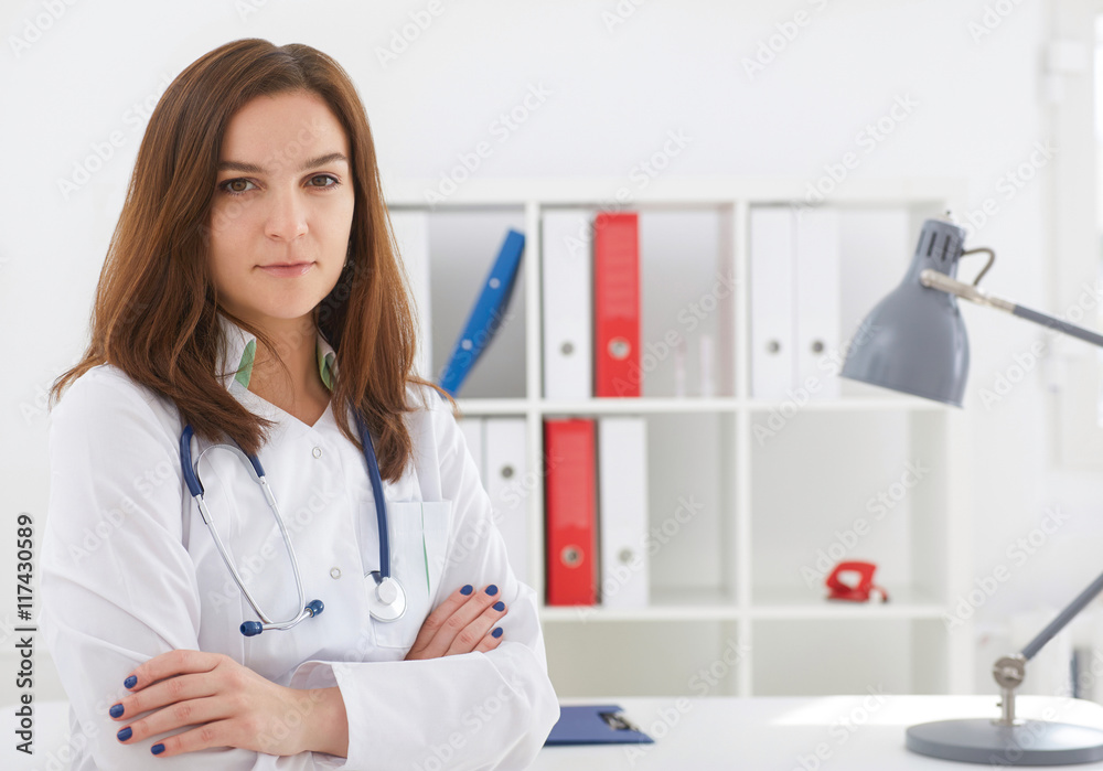 Female medicine doctor with hands crossed on her chest. She look in camera. Medical care or insurance concept. Female medicine doctor with hands crossed on her chest. She look in camera. Medical care or insurance concept.