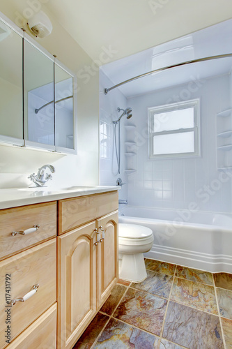 Bathroom interior with light tone vanity cabinet and tile floor.