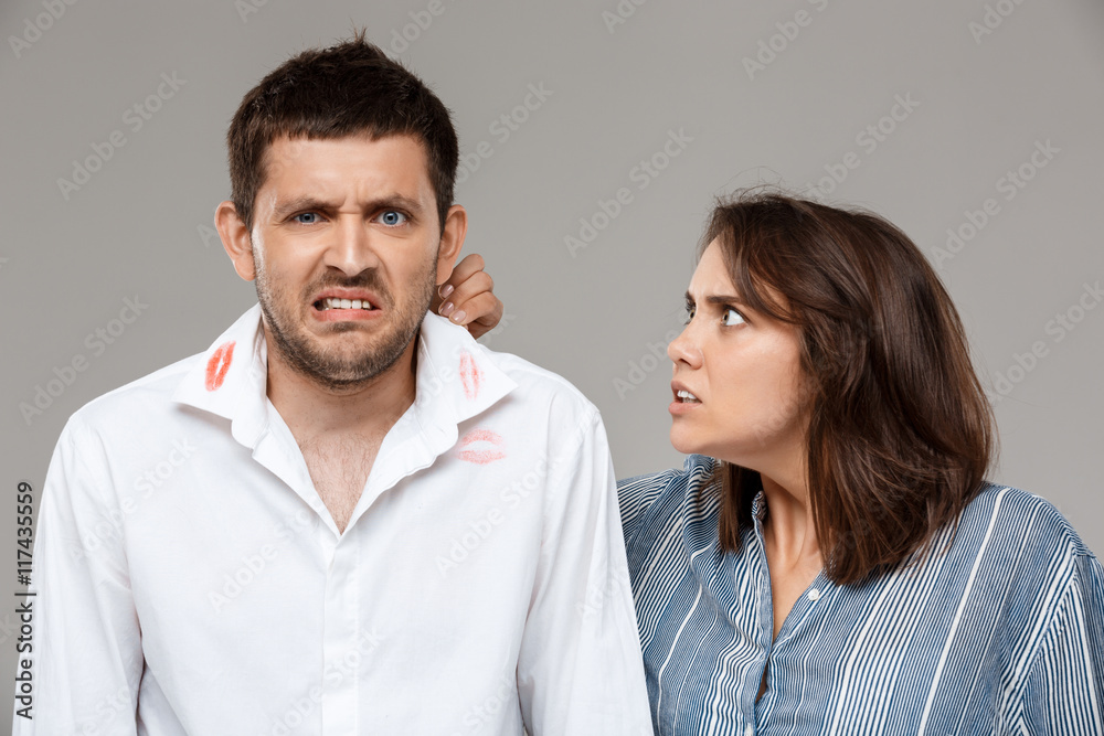 Young woman quarreling, angering with drunk husband over grey background. Young woman quarreling, angering with drunk husband over grey background.