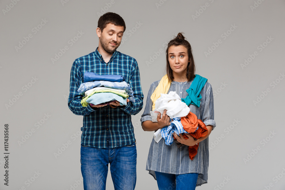 Young beautiful couple holding wash clothes over grey background. Young beautiful couple holding wash clothes over grey background.