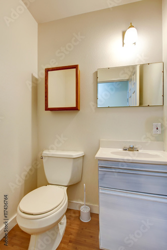 Simple bathroom with small washbasin cabinet and mirror.