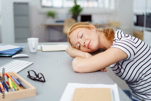 frau schläft am schreibtisch im büro photo