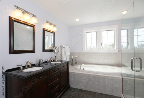 Bathroom with tub and wood cabinet with two sinks