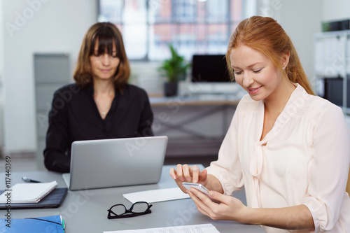 frau im büro schaut auf ihr smartphone