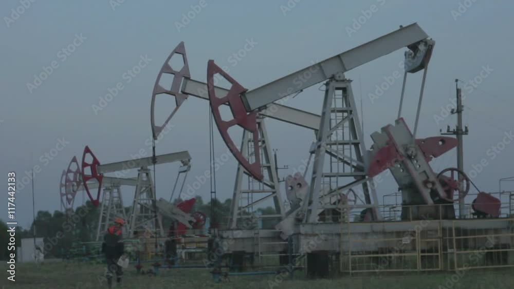 Male Worker with Clipboard Examining Drilling Rig on Pump Jacks Male Worker with Clipboard Examining Drilling Rig on Pump Jacks