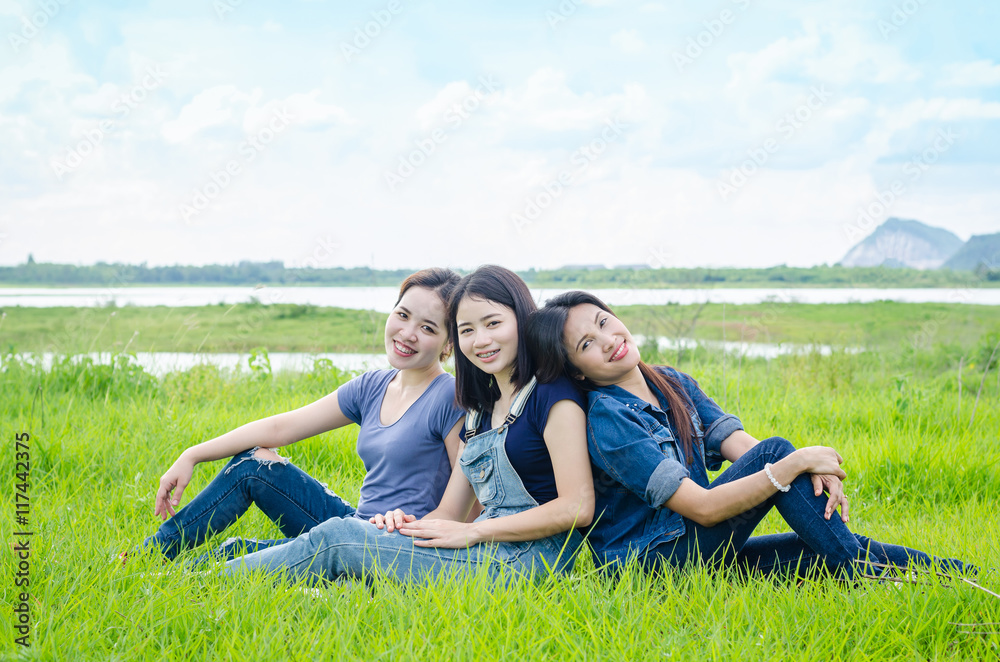 Three beautiful asian women sitting in meadow and smile Three beautiful asian women sitting in meadow and smile