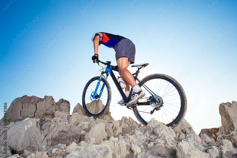 Cyclist Riding the Bike Down Hill on the Mountain Rock