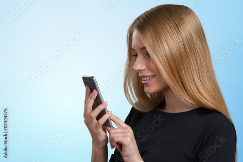 Smiling businesswoman standing and using mobile phone