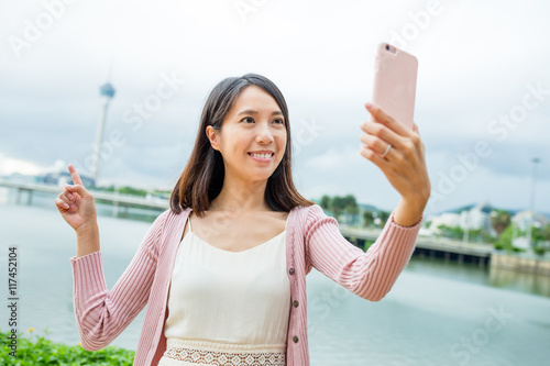 Woman taking selfie by cellphone in Macau city © leungchopan