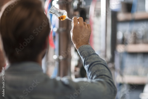 Man in distillery examining glass with liquor