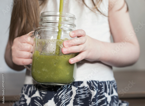 A little girl tasting a green smoothie