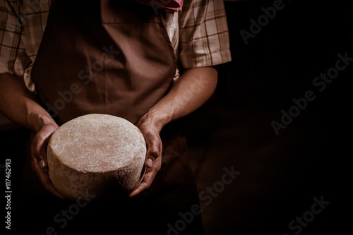 Tableau sur toile Handsome cheesemaker is checking cheeses in his workshop storage.