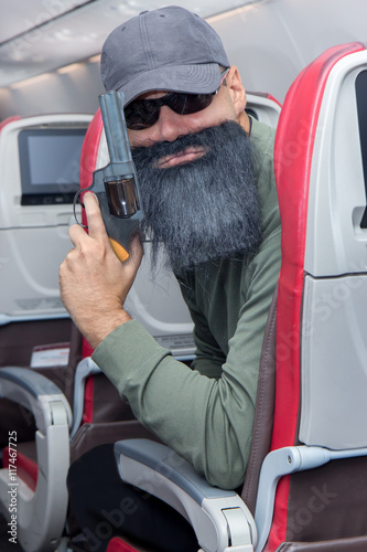 Fotografie bearded terrorist sitting in a flying aircraft, and holds a pistol in his hand