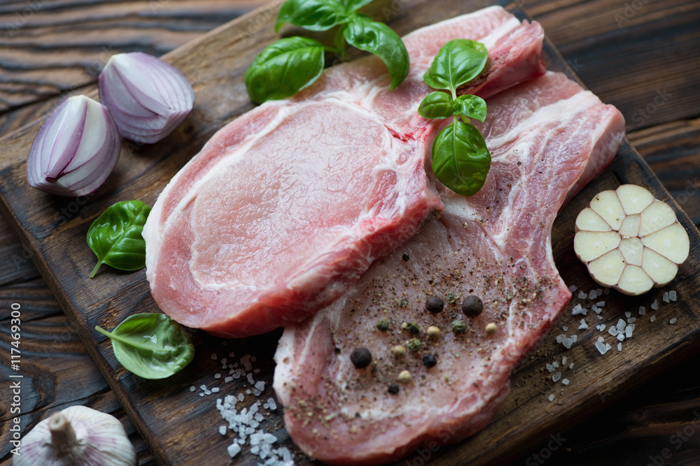 Raw seasoned pork meat cutlets on bone, selective focus Raw seasoned pork meat cutlets on bone, selective focus