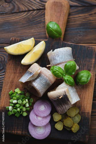 Above view of herring filet rolls with onion, gherkins and lemon