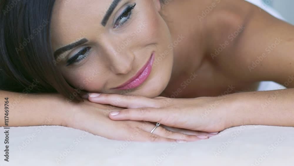 Close up of smart woman's face smiling, looking on camera on the couch. Slowly Close up of smart woman's face smiling, looking on camera on the couch. Slowly