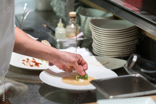 chef dressed in white uniform decorating food 