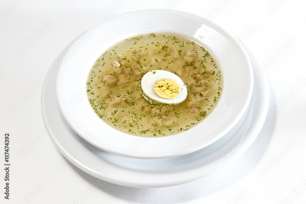 Low-fat chicken broth with a half cooked egg in a bowl isolated on white background Low-fat chicken broth with a half cooked egg in a bowl isolated on white background
