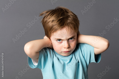 stubborn kid with an attitude ignoring parents scolding, blocking ears photo