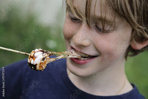Fotografie enfant garçon 10 ans mangeant guimauve fondue au barbecue