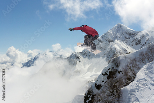 Snowboarder jumps on winter mountain.