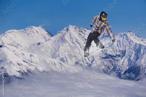 Snowboarder jumps on winter mountain.