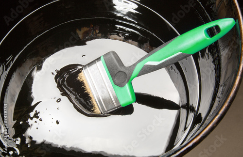 Paint brush in a jar of thick black mastic photo