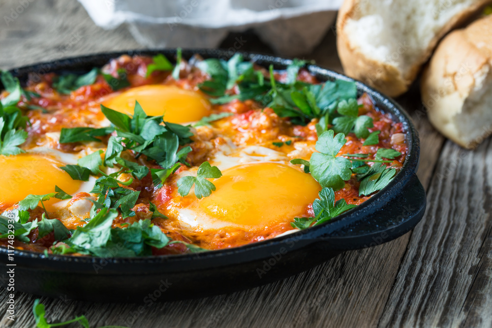 Egg dish with tomato sauce served in cast iron pan, shakshouka Egg dish with tomato sauce served in cast iron pan, shakshouka