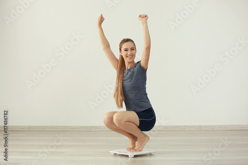Beautiful young woman weigh on floor scales