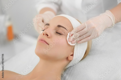 Cosmetologist cleaning woman's face