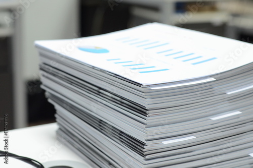 Stack of business reports on desk at workplace with high key tone.
 photo