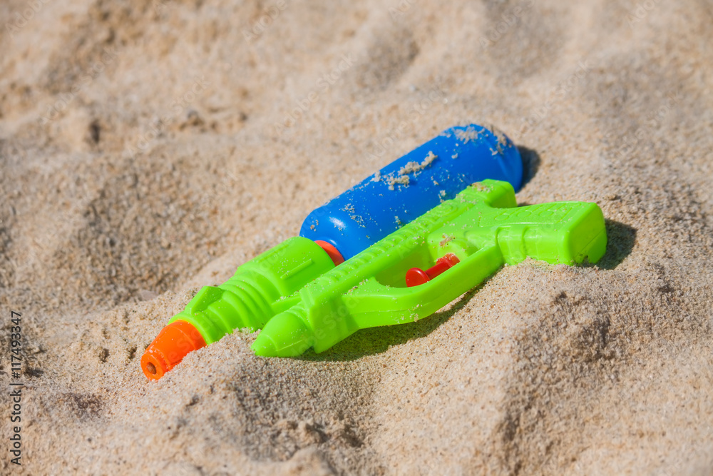 Summer games - Plastic water gun lying in the sand. Summer games - Plastic water gun lying in the sand.