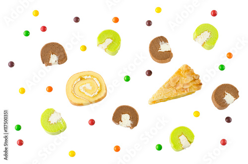 Flat lay image of Swiss roll, corn pie, chocolate and pandan cake rolls with sweet multi-color candies isolated on white background for happy party time celebration or fun and special occasion