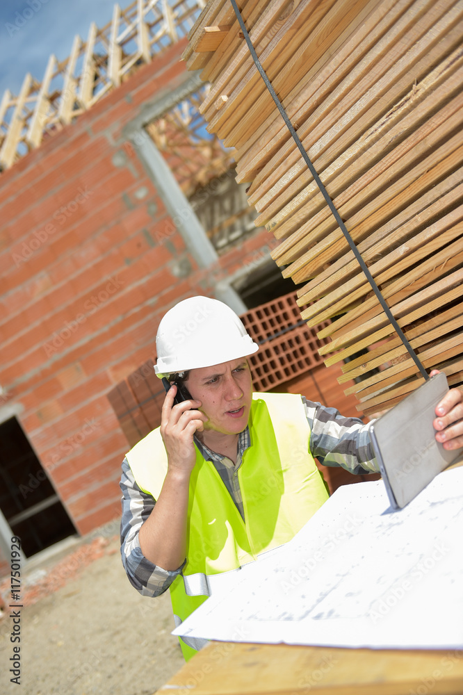 Foreman using walkie-talkie and digital tablet on construction site Foreman using walkie-talkie and digital tablet on construction site