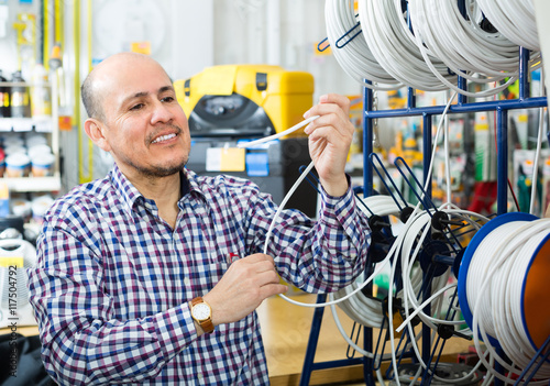 Man choosing cable in household store.
