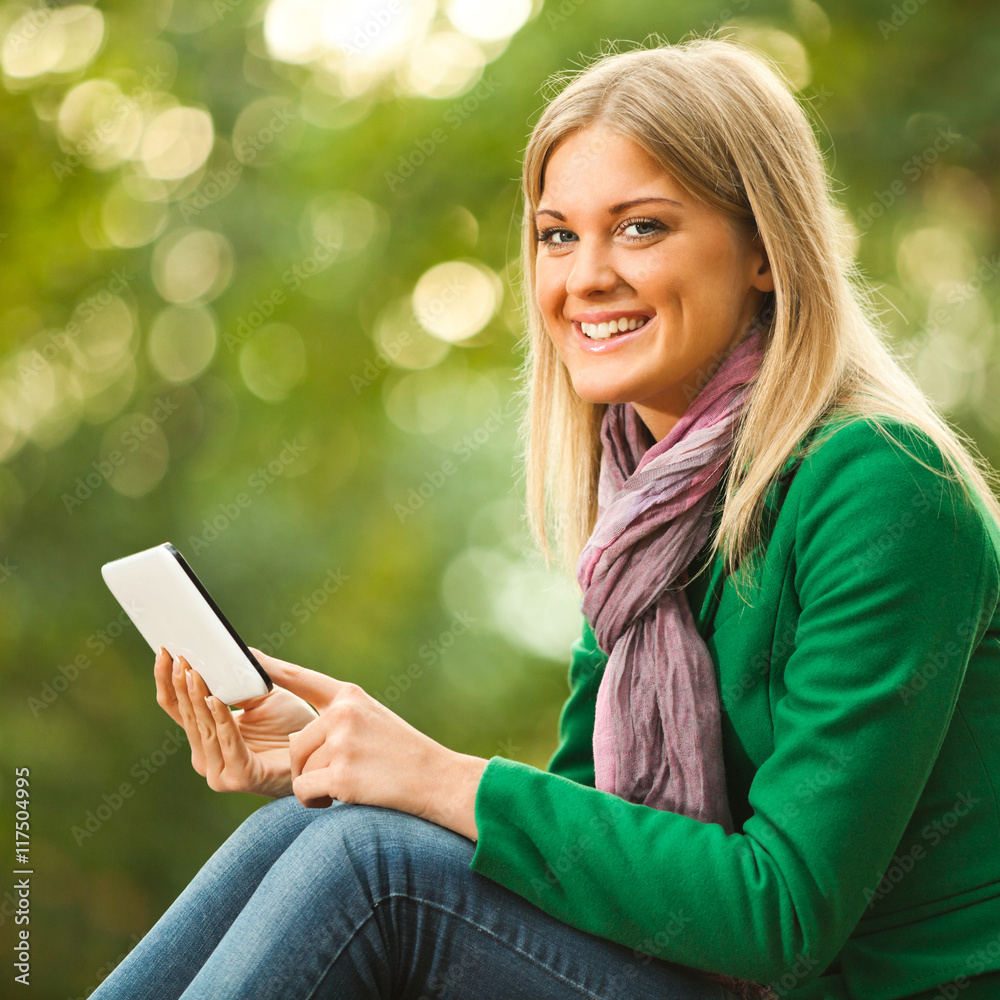 Happy woman is using digital tablet in park. Happy woman is using digital tablet in park.