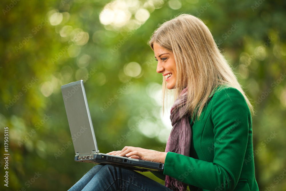 Happy woman is using laptop in park. Happy woman is using laptop in park.