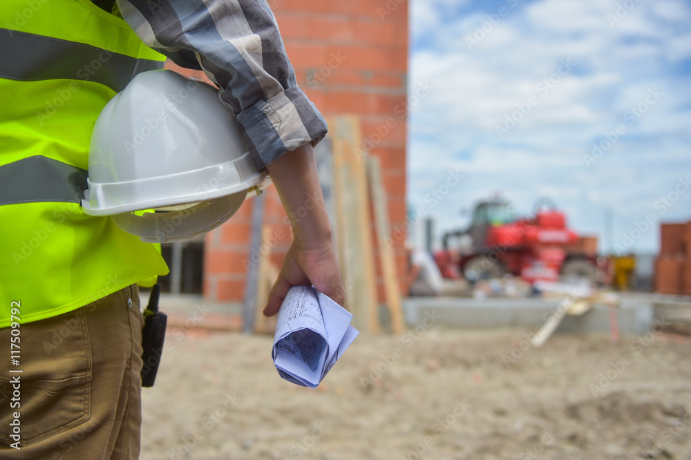 Worker holding a helmet with background of construction site.