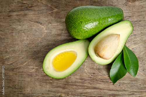 fresh avocado and  avocado like a bowl for oil on wooden backgro