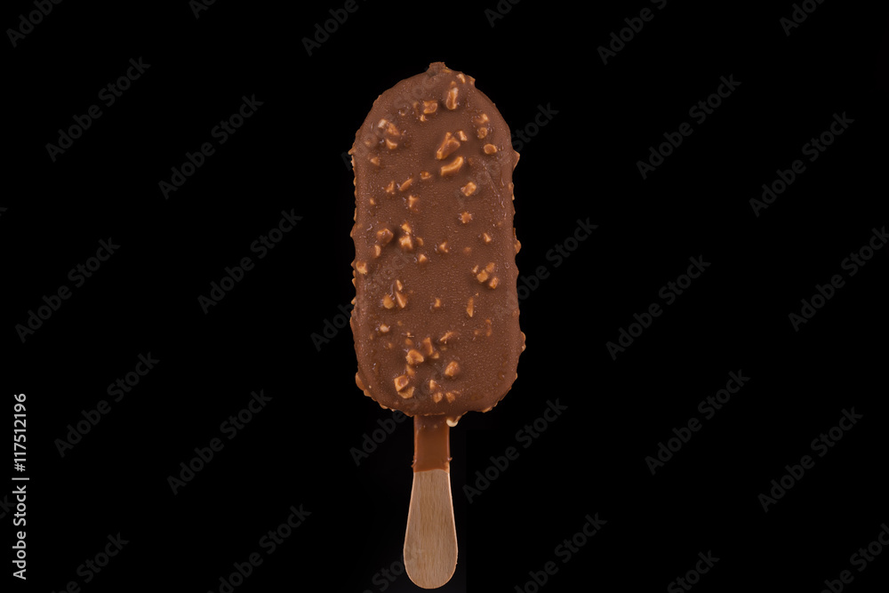 Vanilla ice cream covered with chocolate and peanuts on black background