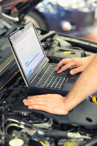 Billede på lærred Fehlersuche Motorelektronik am Auto mit einem Diagnosecomputer in der Werkstatt